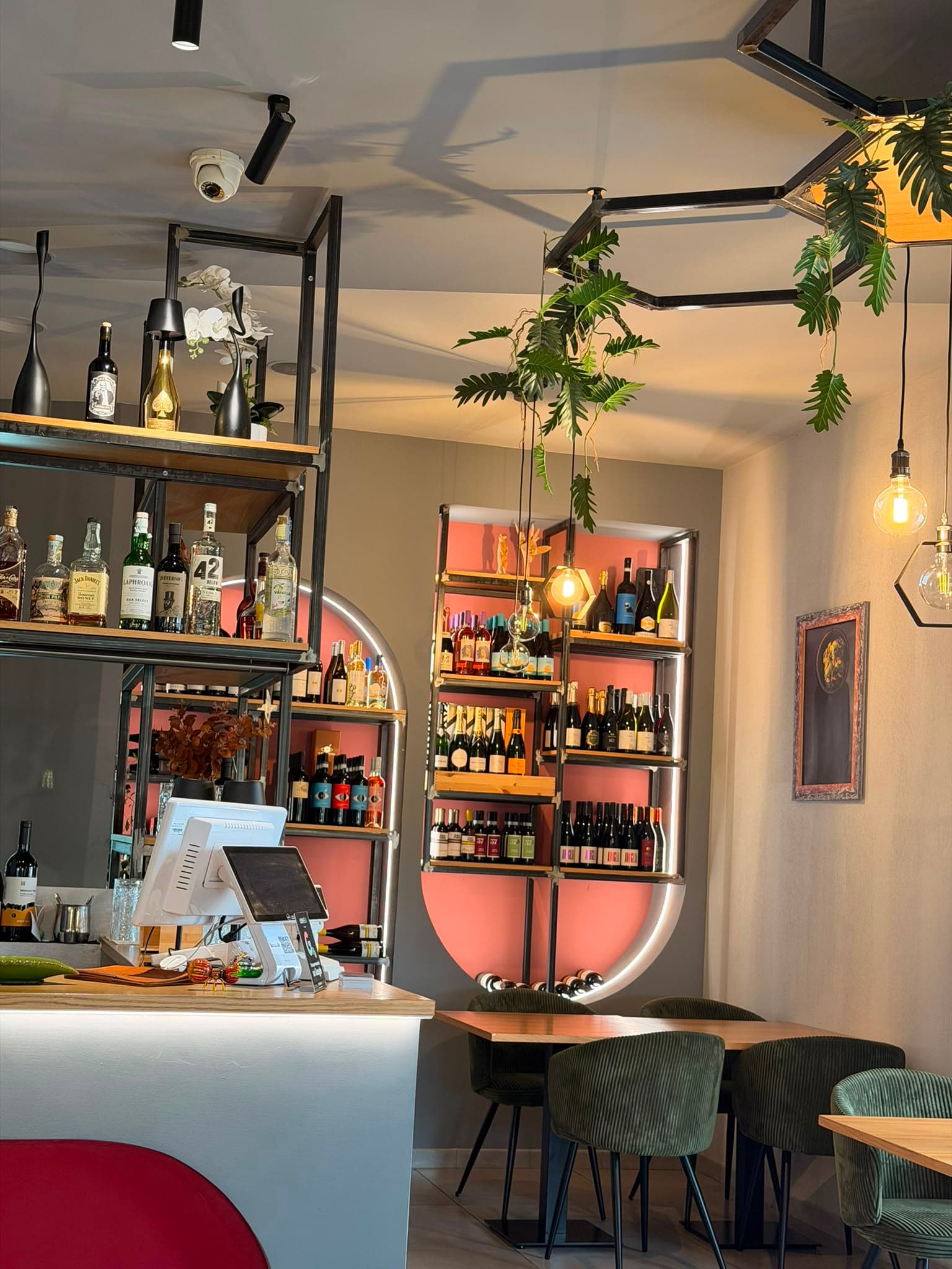 Il bancone e la cantina illuminata di Osmosi, con tavoli e sedute verdi